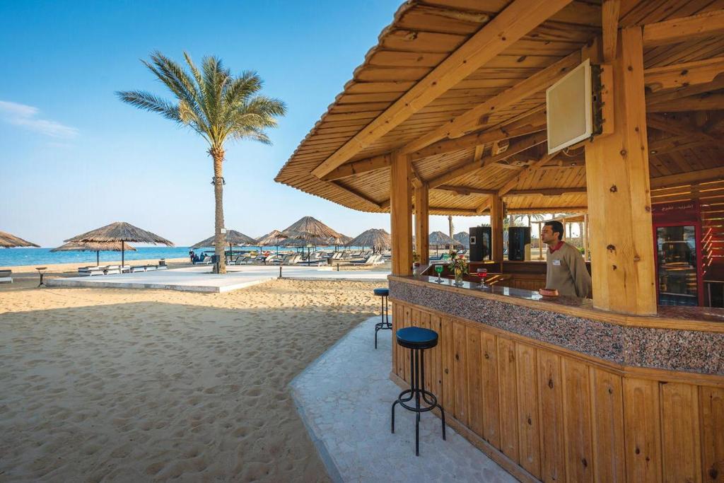 un hombre parado en un bar en la playa en Palmera Chalets Owners Best Vacation Group Families only, en Ain Sokhna