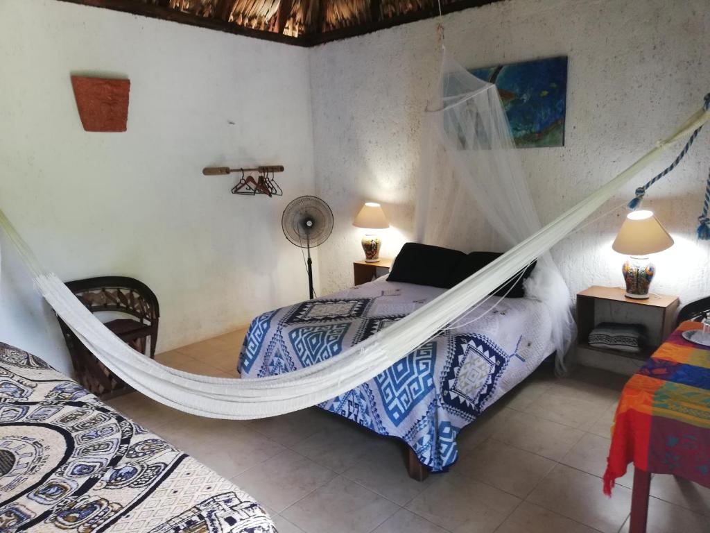 ein Schlafzimmer mit 2 Betten und einer Hängematte. in der Unterkunft Mayan Bungalow Near Chichén in Chichén Itzá