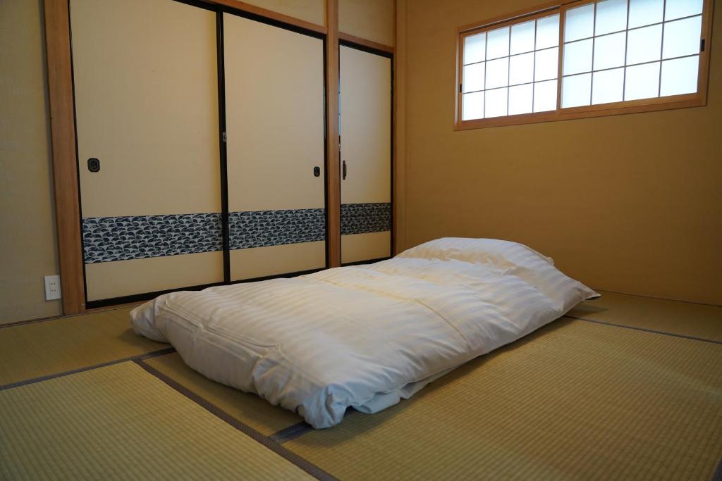ein großes weißes Bett in einem Zimmer mit Fenster in der Unterkunft 吹屋庵 in Takayama