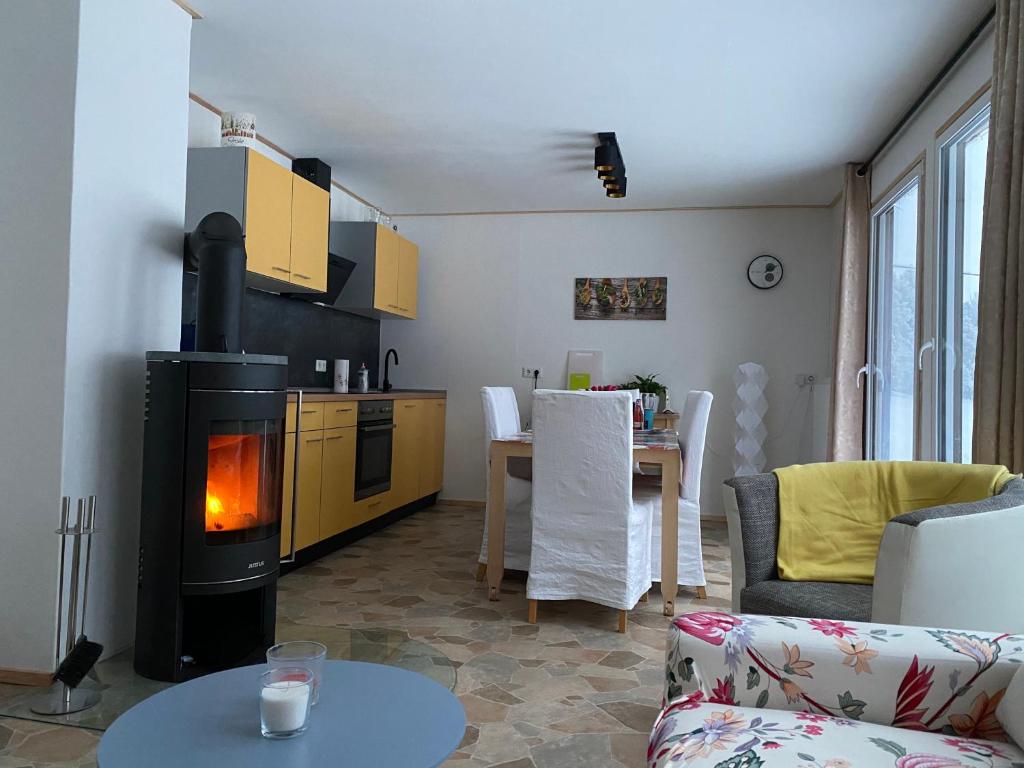 a living room with a stove and a kitchen at Ferienanlage Geisingblick in Geising