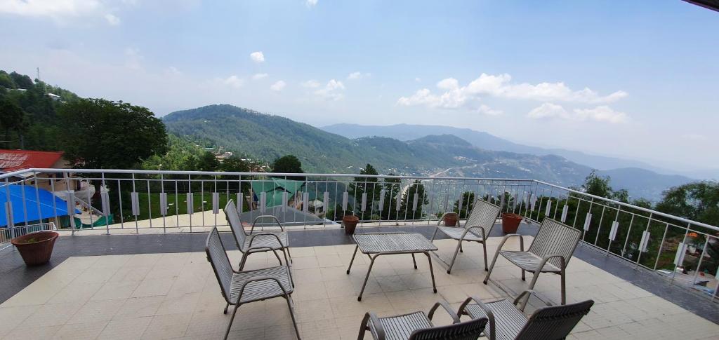 a group of chairs and tables on a balcony with mountains at Mountain Retreat at Afgan Lodge in Murree