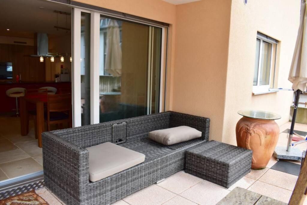 a wicker couch sitting on a porch with a vase at Modern Apartment 모던 펜션 in Interlaken