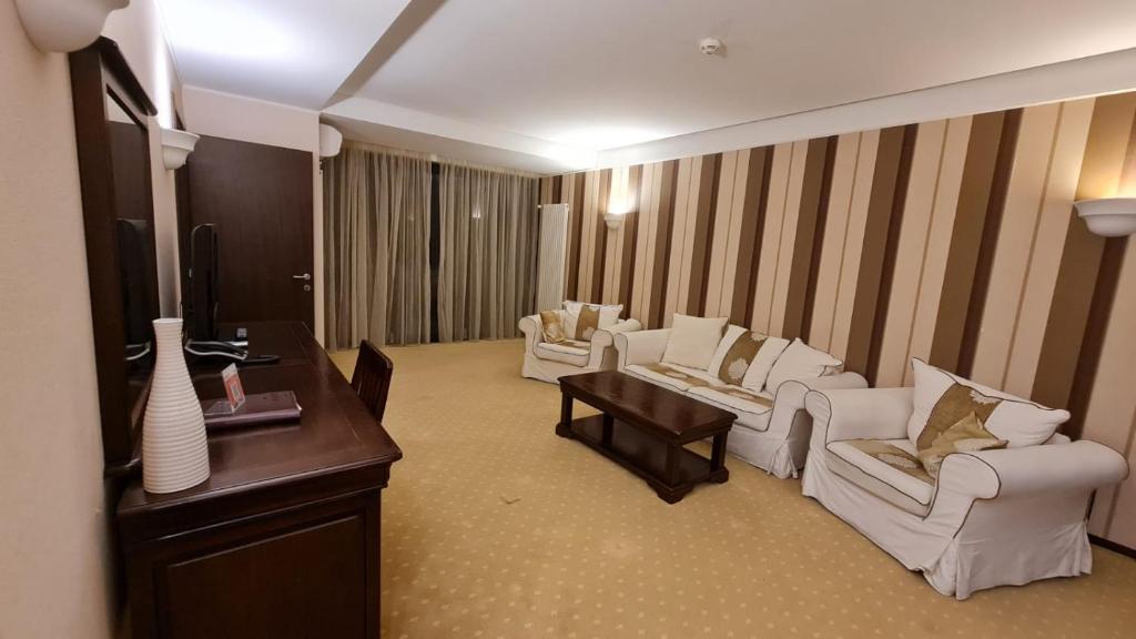 sala de estar con sillas blancas, mesa y TV en Apartment Privat ApartHotel Alpin fara mic dejun si fara acces SPA, en Poiana Brasov
