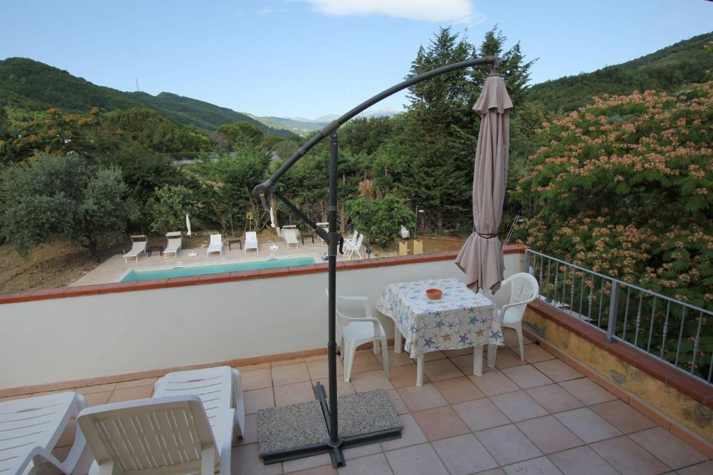 un patio con sombrilla, mesa y sillas en Teramo 1 dall'Adriatico al Gran Sasso con Piscina, en Teramo
