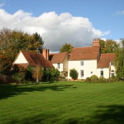 un grupo de casas en un campo de césped verde en Stoke by Nayland B&B Poplars Farmhouse, en Stoke-by-Nayland