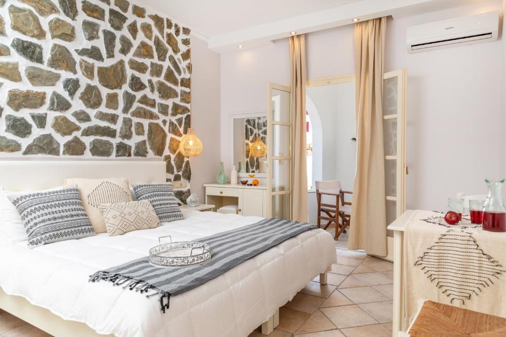 a bedroom with a bed with a stone wall at GOLDEN COAST NAXOS in Agios Prokopios