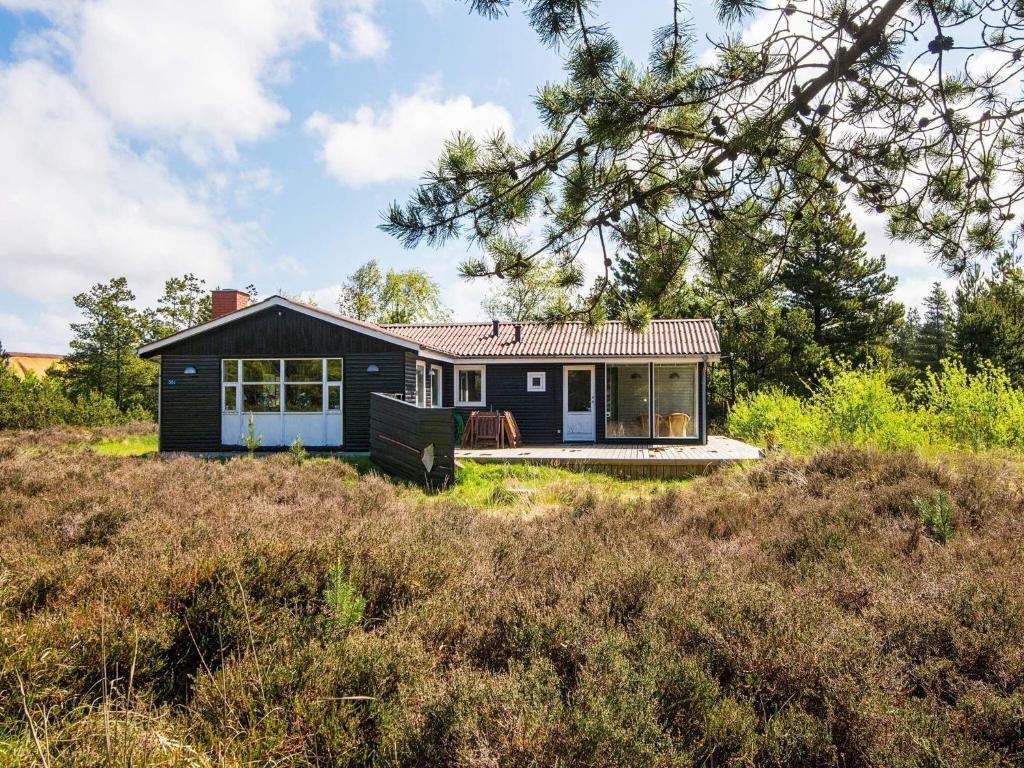 een klein blauw huis op een heuvel in een veld bij 6 person holiday home in R m in Kongsmark