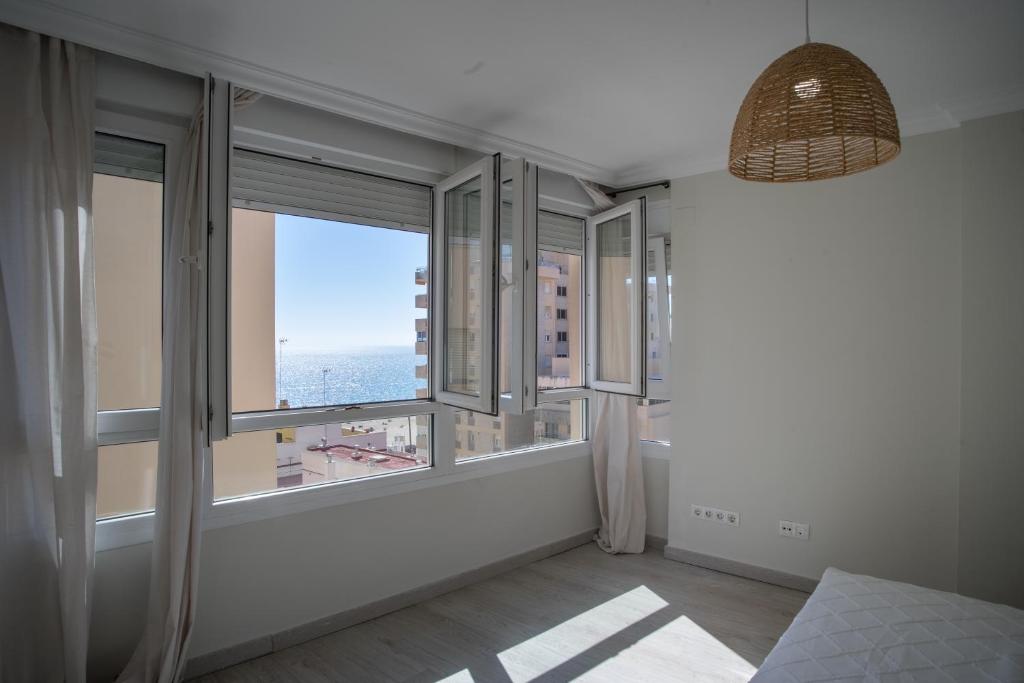 een kamer met grote ramen met uitzicht op de oceaan bij Playa Victoria Ha Apartment in Cádiz