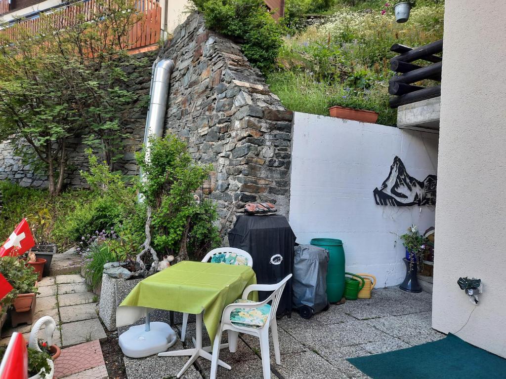 a patio with a table and chairs and a wall at Bodmen 3 Apartments von Privat in Zermatt in Zermatt