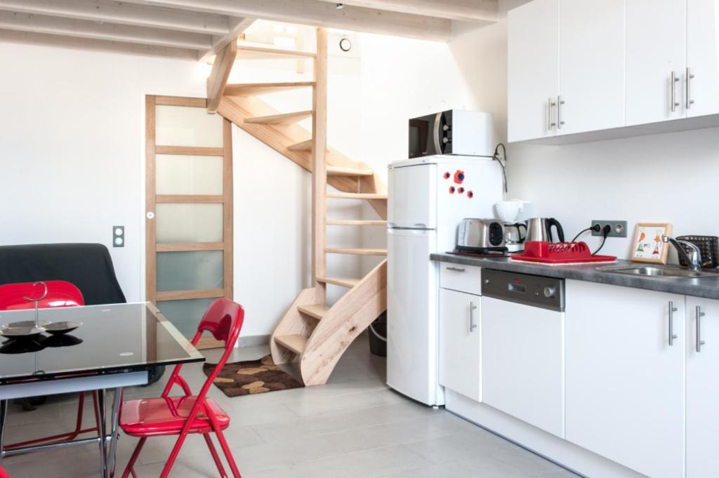Il comprend une cuisine équipée d'un réfrigérateur et d'une table avec des chaises rouges. dans l'établissement Superbe T1 bis de 35 m2 - stationnement gratuit - proche gare et port - Apt Droit, à La Rochelle