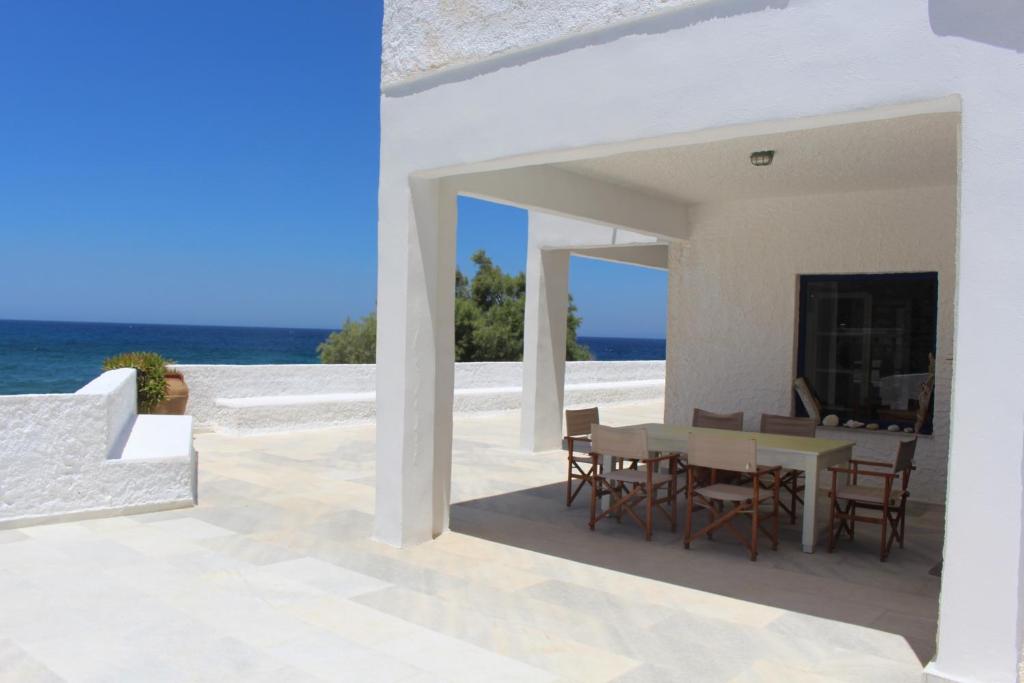 uma casa branca com uma mesa e cadeiras e o oceano em Villa Akrotiri – The Star Watcher em Engares