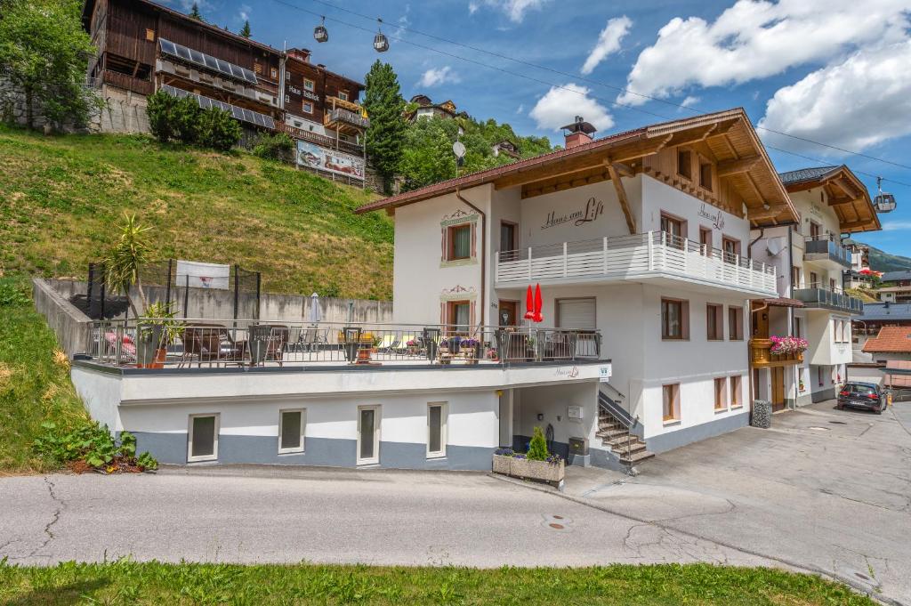 a white building with a balcony on a hill at Haus am Lift in Kappl