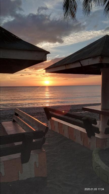 a sunset on the beach with tables and umbrellas at The Waterfront Beach Resort in Morong