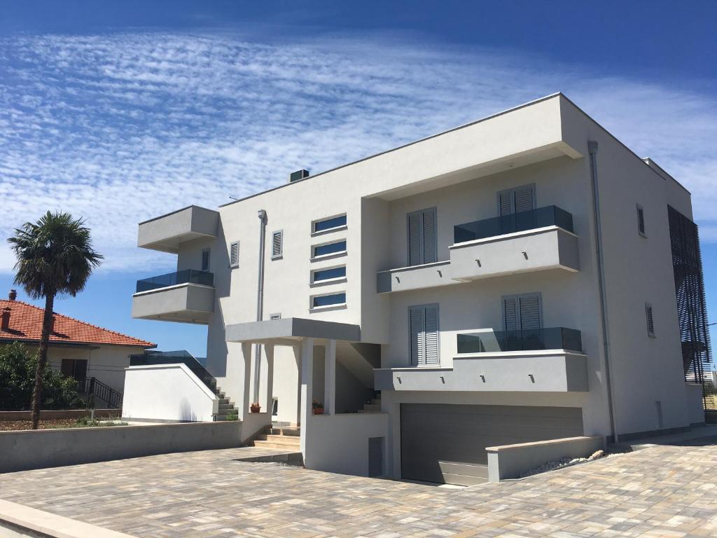 een wit gebouw met balkons en een palmboom bij Villa Tragurium in Trogir