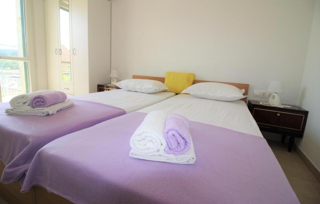 2 camas con toallas moradas y blancas. en Privatna Soba Gita, en Sumartin