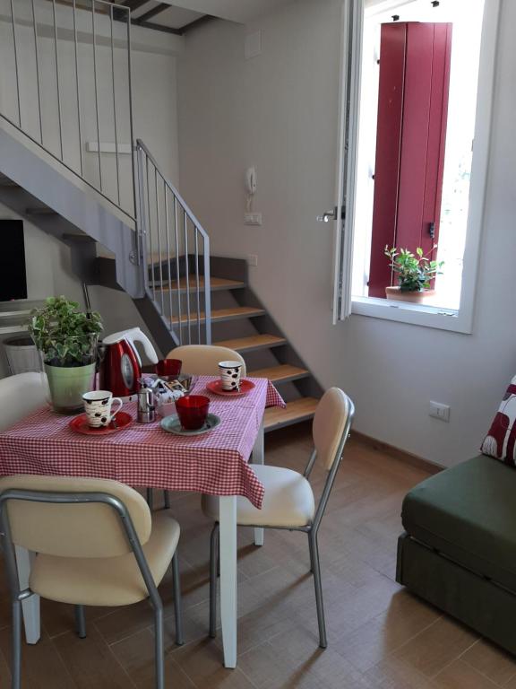 una sala da pranzo con tavolo e sedie rossi e una scala di Appartamento Augusta a Vittorio Veneto