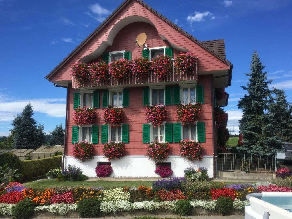 una casa con flores a un lado. en Apartment auf dem Bauernhof, en Lucerna