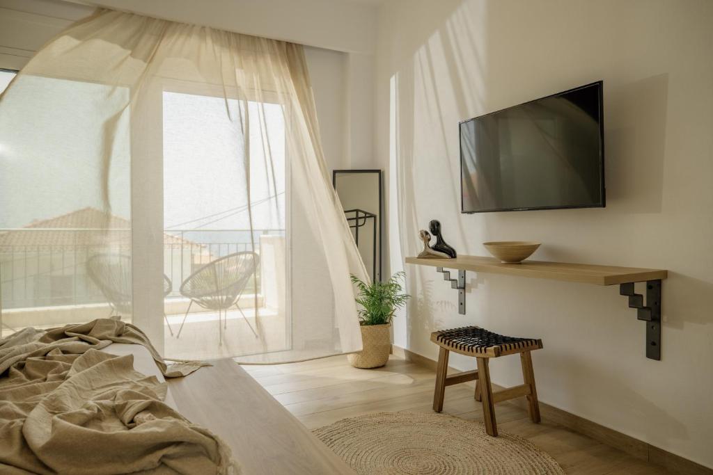a living room with a bed and a tv and a window at Casa Costa Suites in Kanali