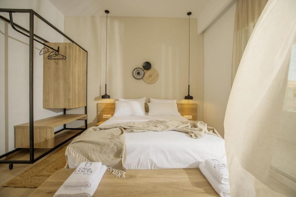 a bedroom with a bed with white sheets and pillows at Casa Costa Suites in Kanali