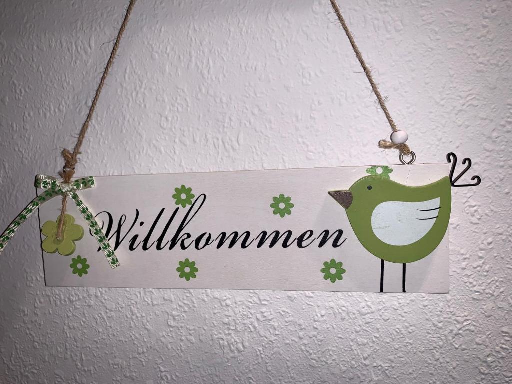 a sign hanging on a wall with a green bird at Gästehaus Am Radweg in Blieskastel