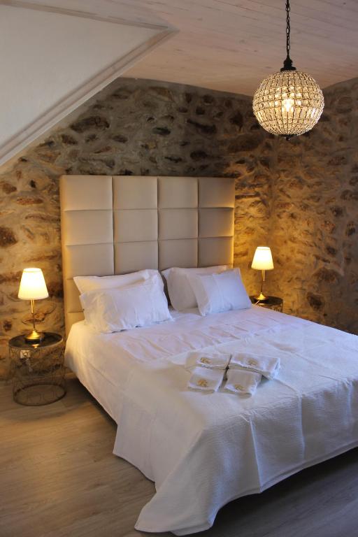 ein Schlafzimmer mit einem großen weißen Bett mit zwei Gläsern darauf in der Unterkunft Casas Tomé - Turismo Rural - Country Houses in Frechão