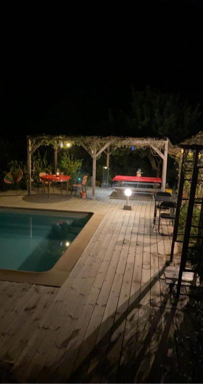 a patio with a table and a pool at night at B&B Macchia Verdata avec piscine in Monacia-dʼAullène