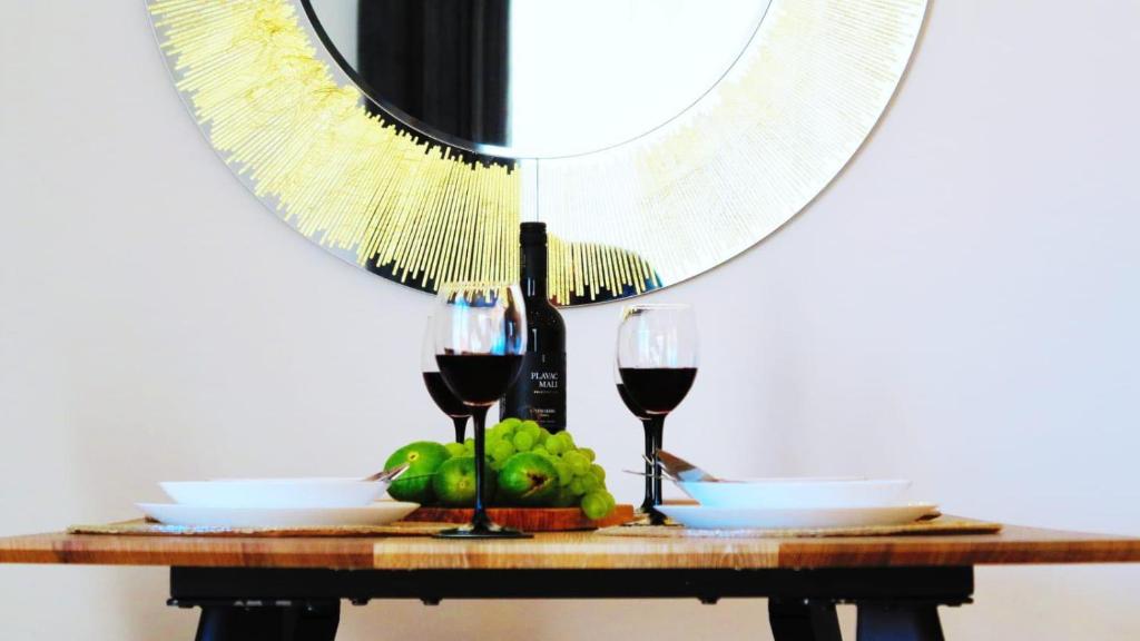 a table with two glasses of wine and a mirror at Casari rooms & apartments in Split