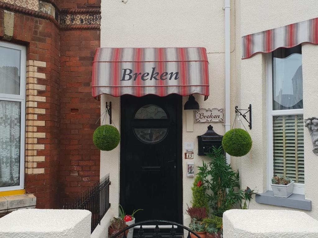 una puerta negra a una panadería con toldo rojo y blanco en Breken Guest House, en Exmouth