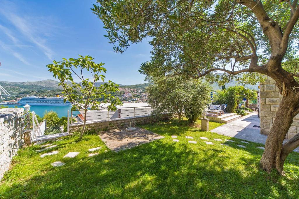 a green yard with a tree and a bench at Villa Jolanda Apartments in Dubrovnik