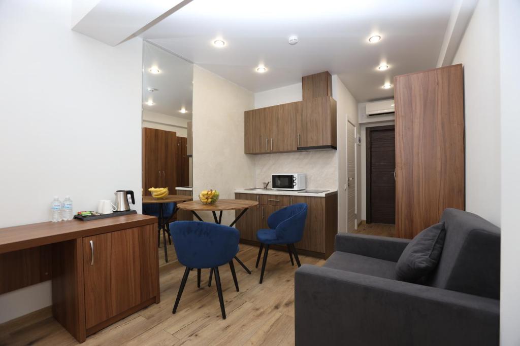 een woonkamer en een keuken met een bank en een tafel bij Апарт отель Ривьера Парк in Sotsji