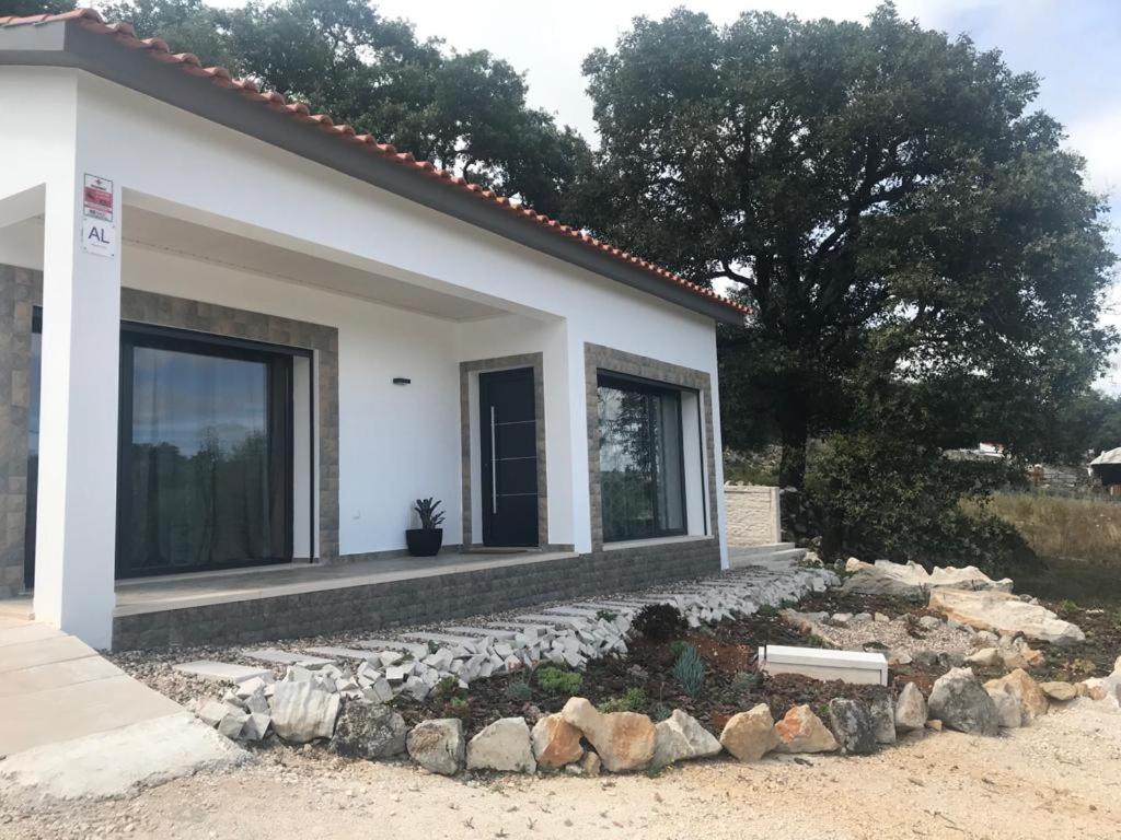 uma pequena casa branca com um monte de pedras à frente. em Recanto da Serra em Porto de Mós