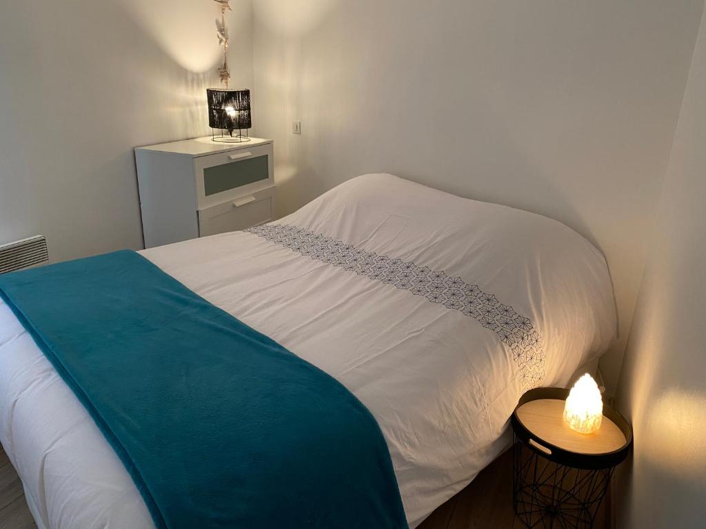 niewielka sypialnia z białym łóżkiem i niebieskim kocem w obiekcie Bêêê de Somme w mieście Saint-Valéry-sur-Somme