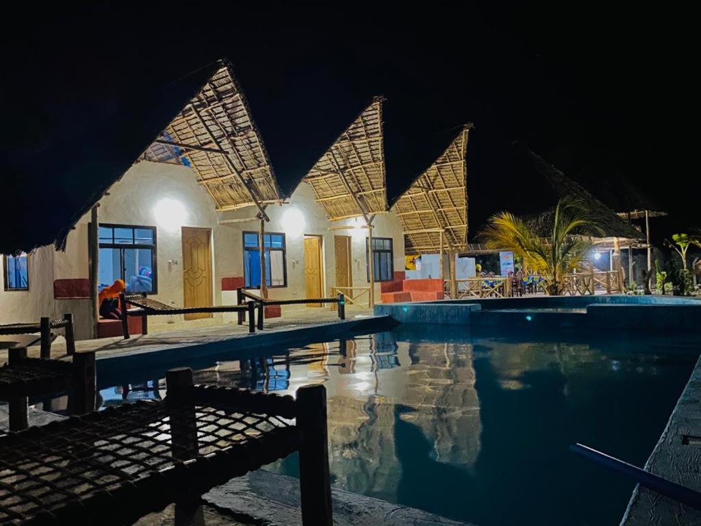 a swimming pool in front of a building at night at Mkeka Spice Lodge Jambiani in Jambiani
