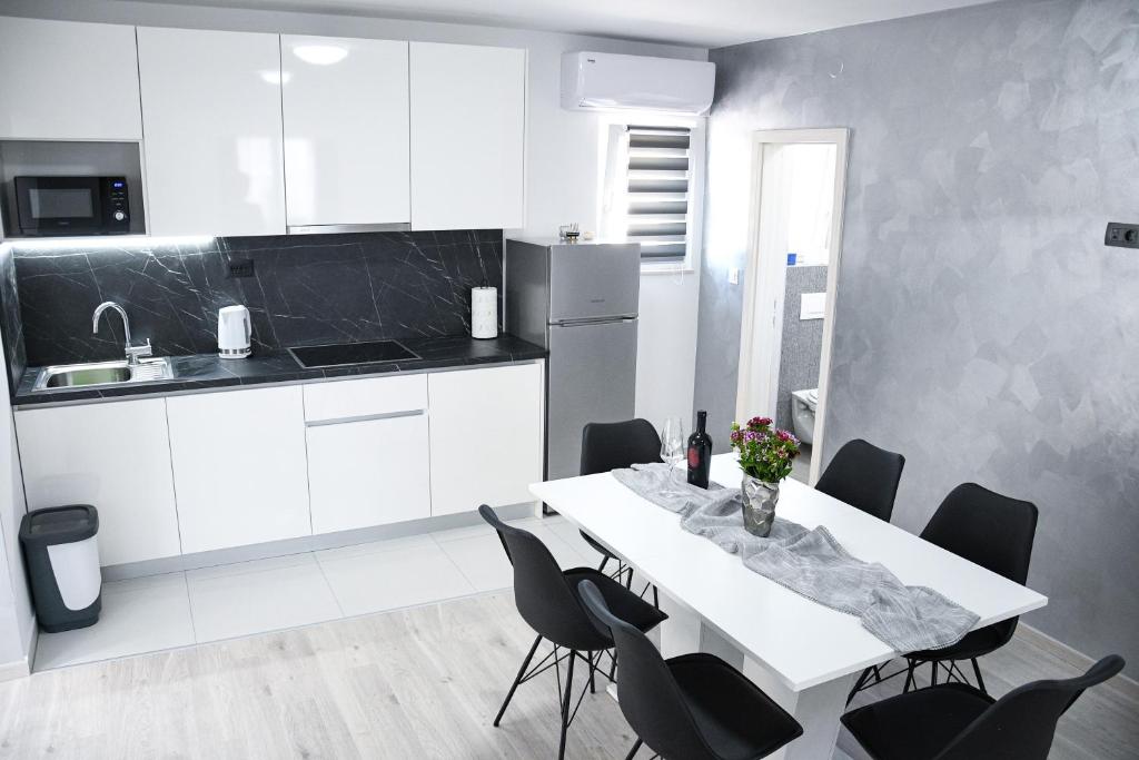 cocina blanca con mesa blanca y sillas en Apartment Light en Stobreč