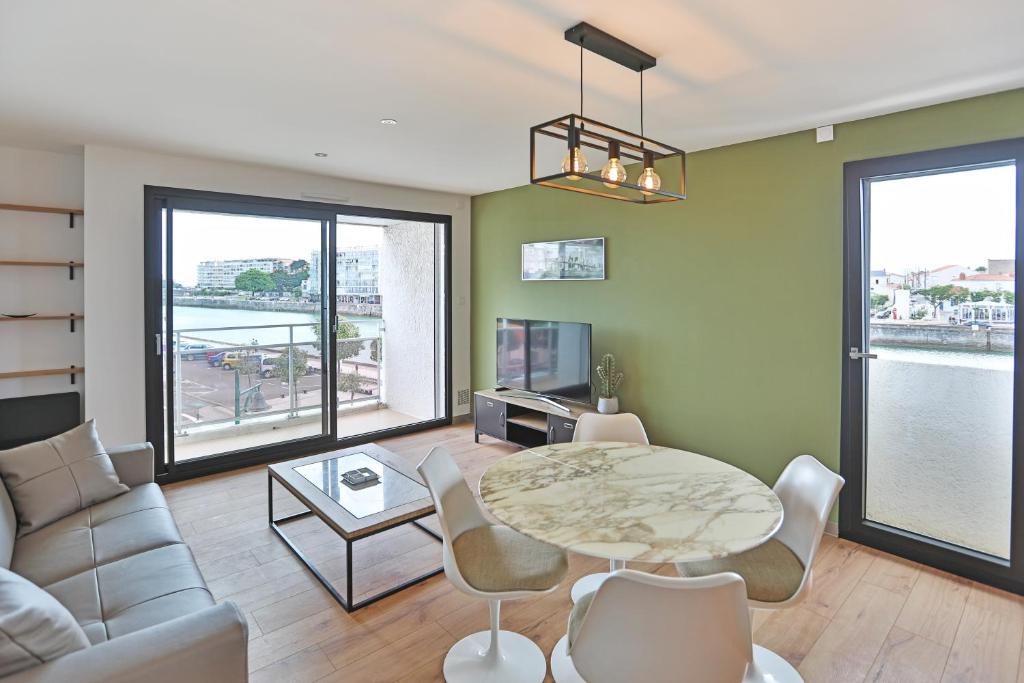 a living room with a table and a couch at Vue panoramique mer et chenal même de la chambre 50m2 refait à neuf situation idéale en option garage fermé privé in Les Sables-dʼOlonne