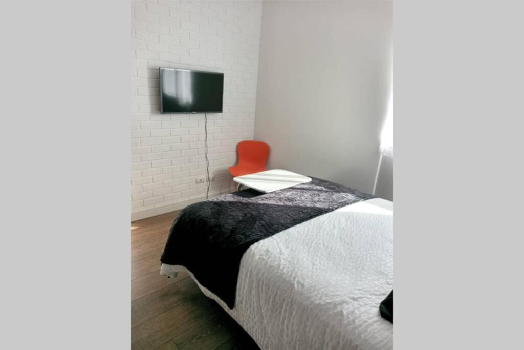 um quarto com uma cama e uma cadeira vermelha em Estudio Monoambiente em Cochabamba