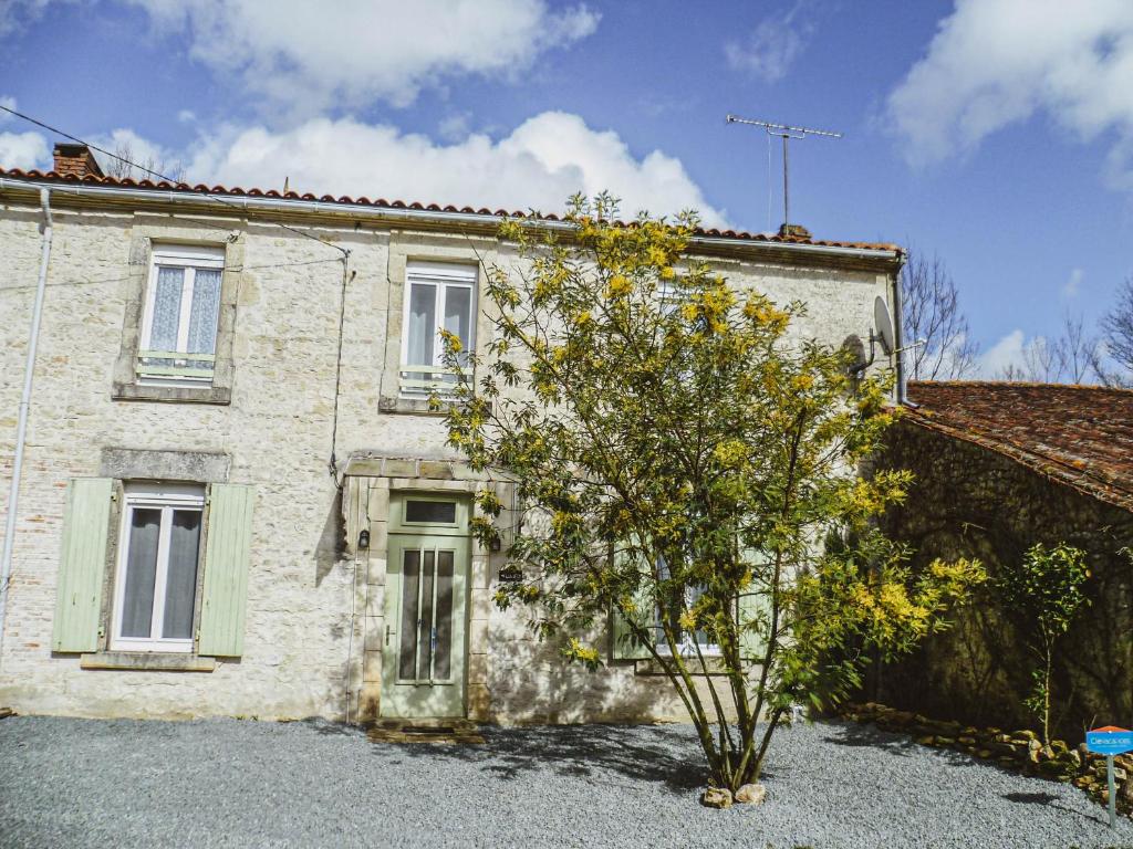 una casa con un árbol delante de ella en LA LAUJÈRE IVIE - Gîte & Piscine privative, en Saint-Hilaire-du-Bois