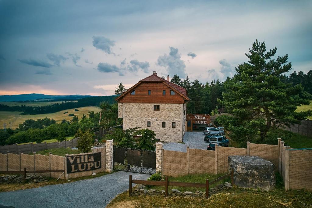 a building with a fence next to a parking lot at Villa LUPU in Smižany