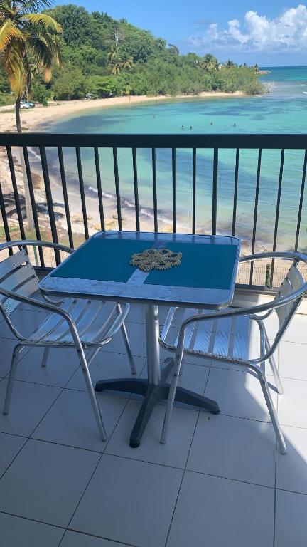 einen blauen Tisch und Stühle auf einem Balkon mit Blick auf den Strand in der Unterkunft Rêve bleu in Le Gosier