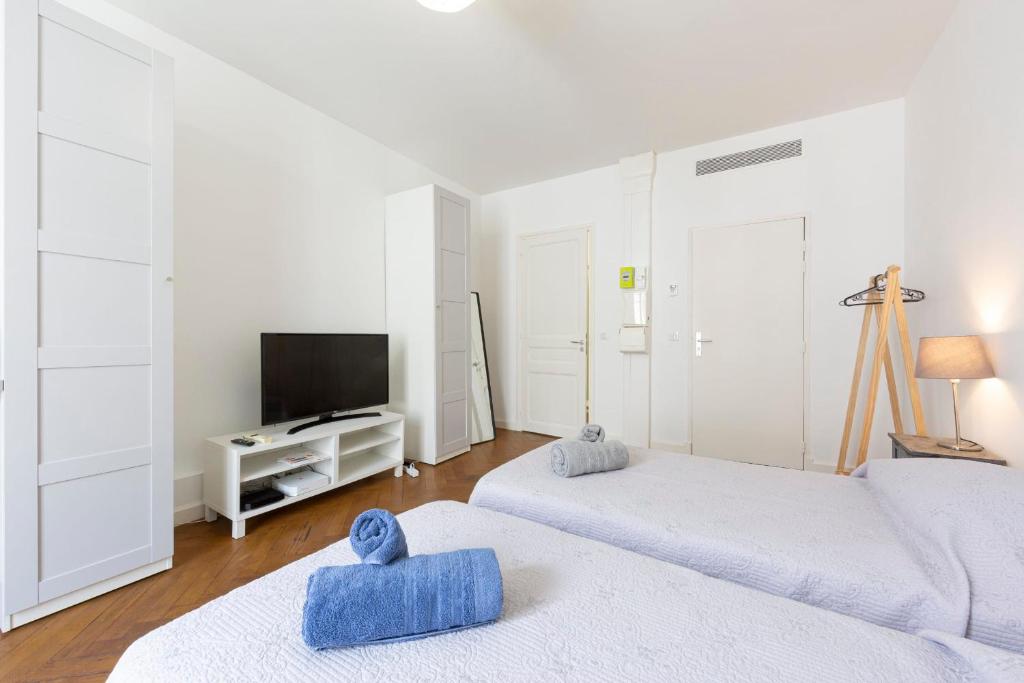 Cette chambre blanche comprend deux lits et une télévision. dans l'établissement Cosy apartment 27 m2 in rue d'Antibes and Croisette, à Cannes