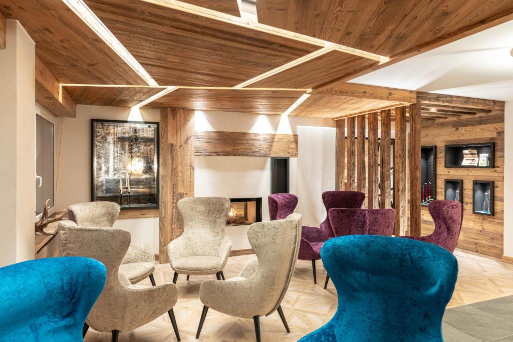a waiting room with blue chairs and wooden ceilings at Alpstyle Hotel Albolina Wellness & Beauty in Canazei