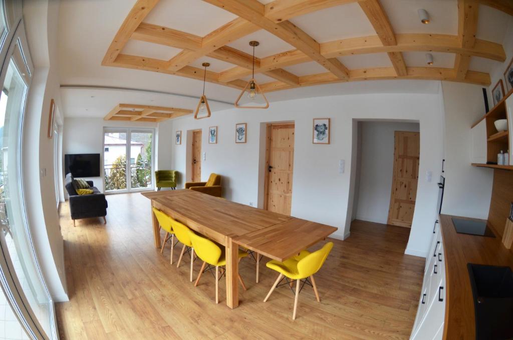 een keuken en eetkamer met een houten tafel en gele stoelen bij HARLEY FAMILY APARTAMENT in Muszyna