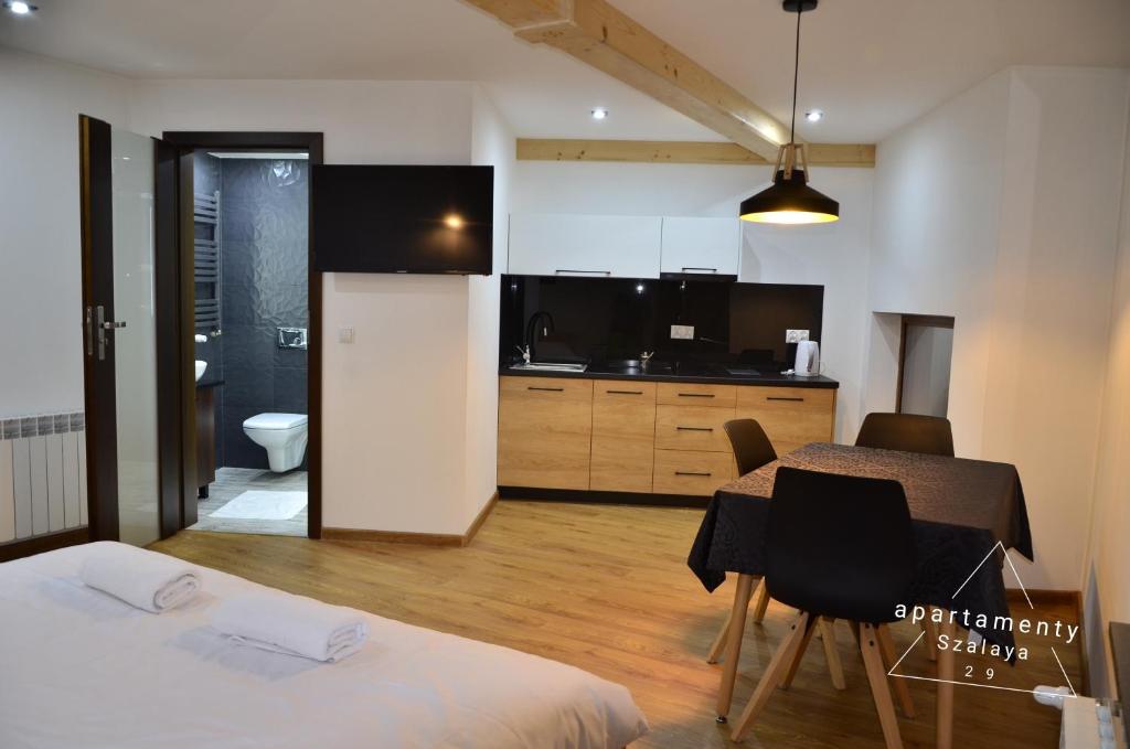 a room with a dining table and a kitchen at Apartamenty Szalaya 29 in Szczawnica