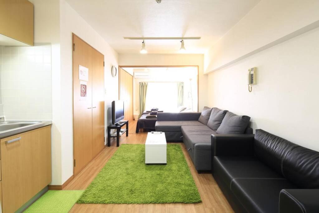 sala de estar con sofá negro y alfombra verde en 【渋谷35】光回線完備のお部屋＜Rewrite＞, en Tokio