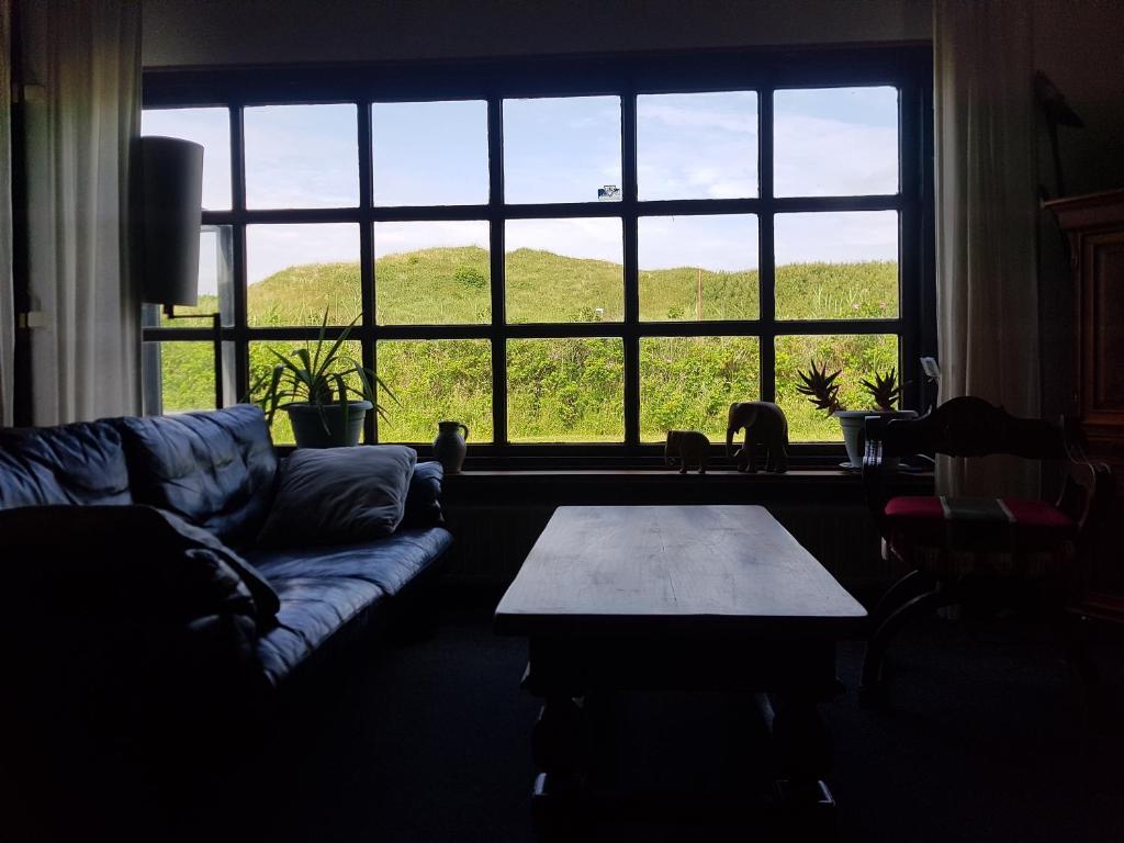 a living room with a couch and a table in front of a window at Julianadorp Direkt an den Dünen in Julianadorp