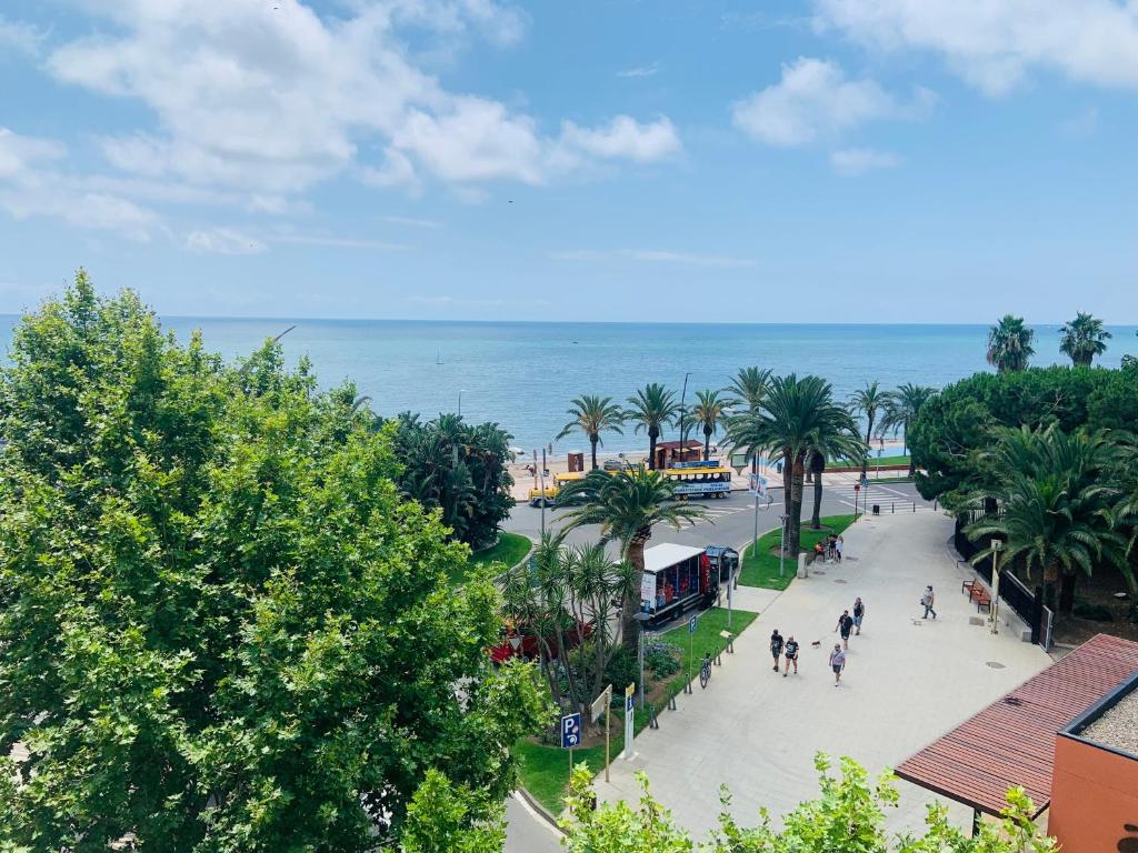a view of a street with palm trees and the ocean at Apartamento Vela Cambrils Playa in Cambrils