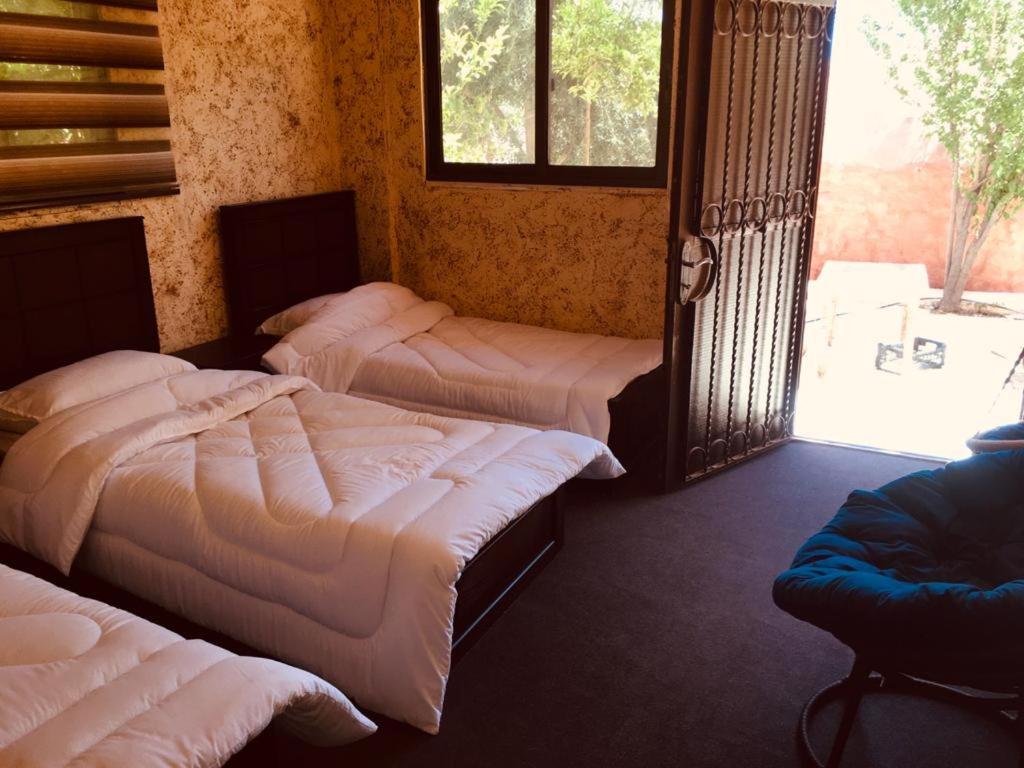 three beds in a room with a window at Petra bedouin house in Al Ḩayy