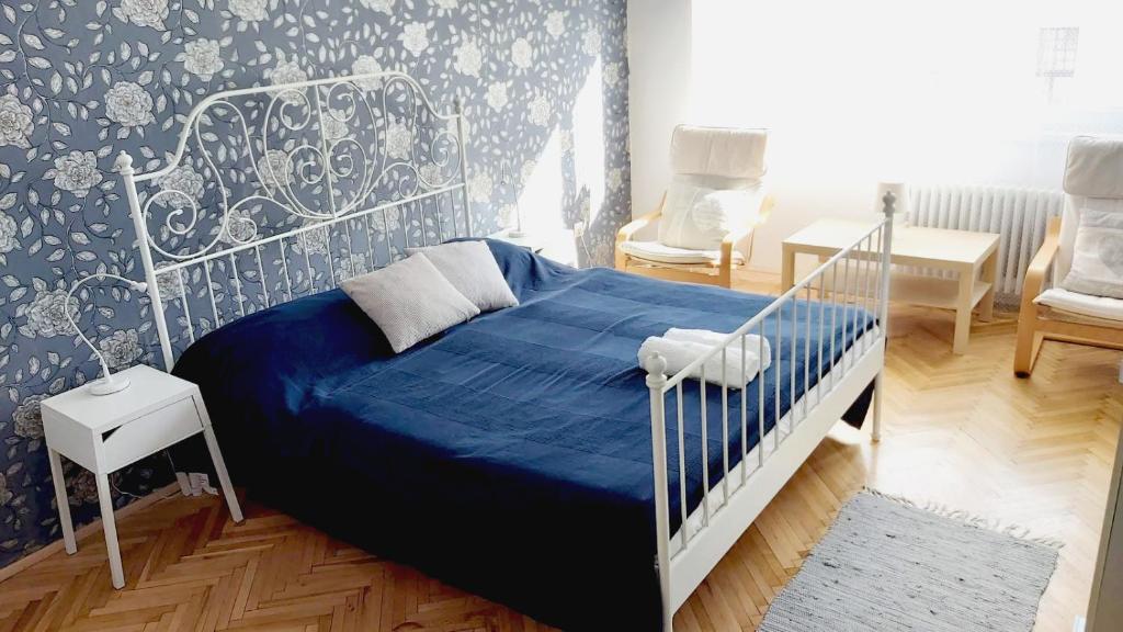 een slaapkamer met een bed met een blauw dekbed bij Eozin Apartman in Pécs