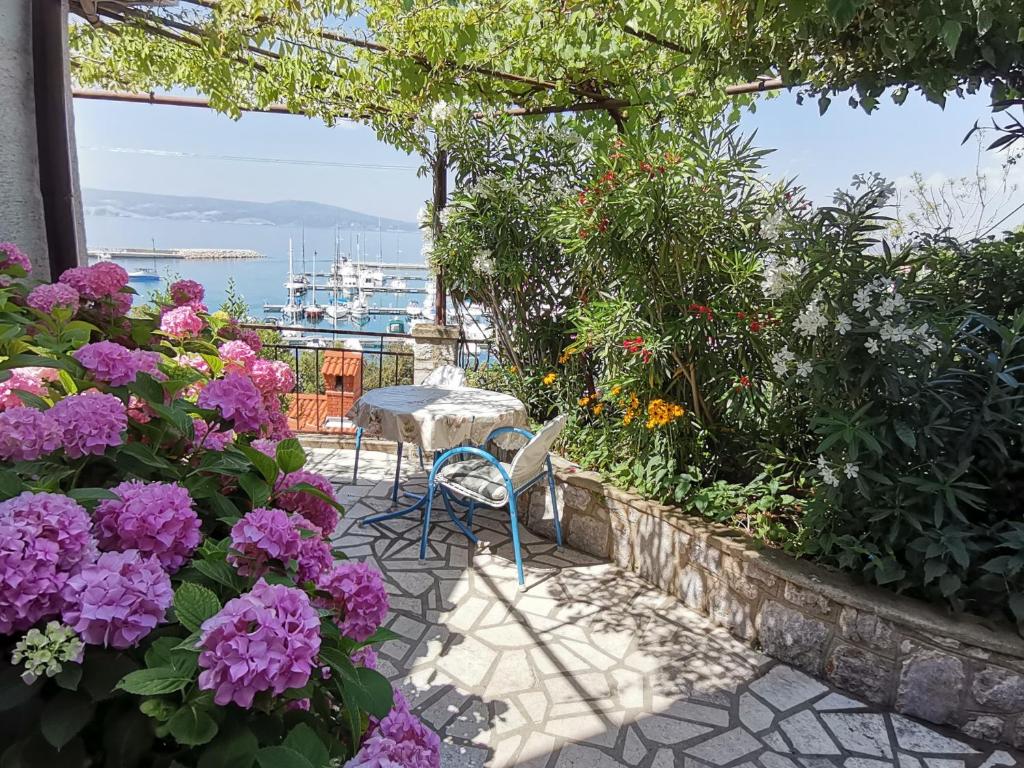 a patio with purple flowers and a table and chairs at Holiday house Belavista in Novi Vinodolski