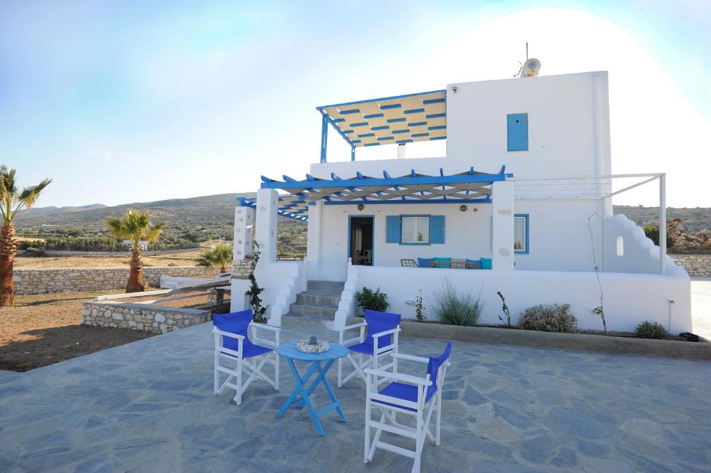 a white house with blue chairs and a table at Villa Aspa Paros in Dhragoulás